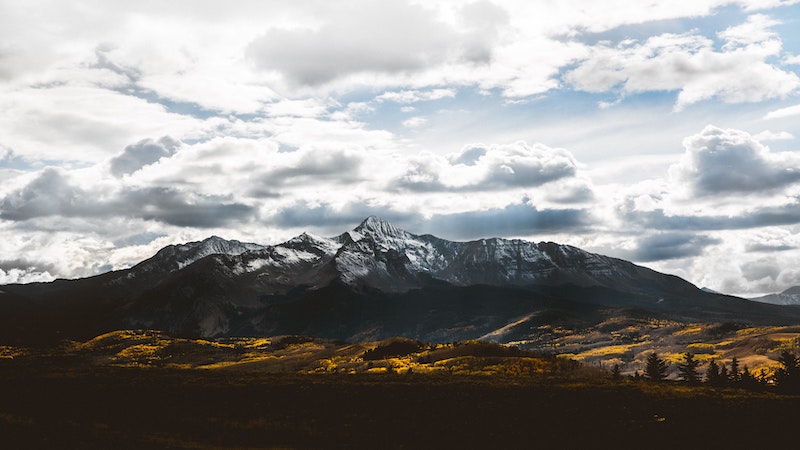 sunlit clouds with a lightly snowed upon Mount Wilson and yellow aspen trees in the foreground