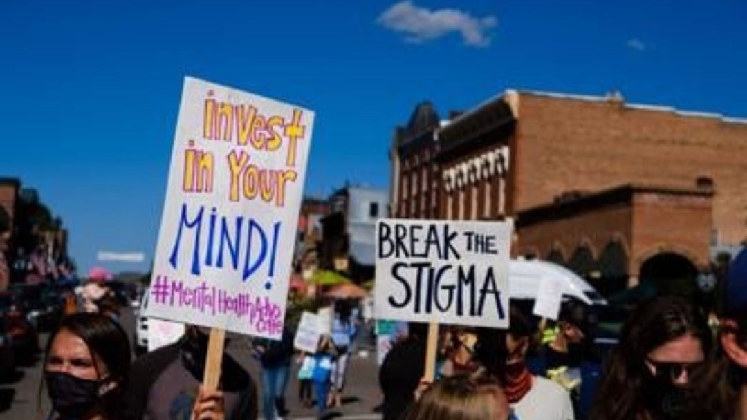 Picket signs with messages supporting mental health care on Telluride's main street with blue sky in the background