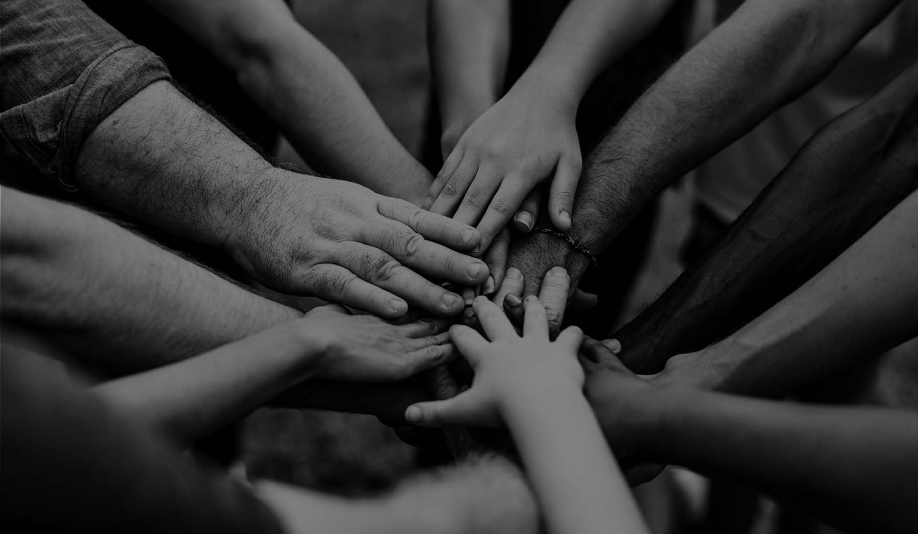 Diverse hands coming into the center of the photo in black and white