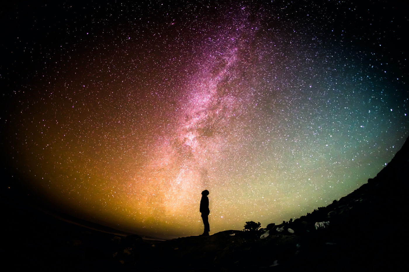 Man silhouette looking at a colorful star filled sky with purple milky way with fisheye lense 