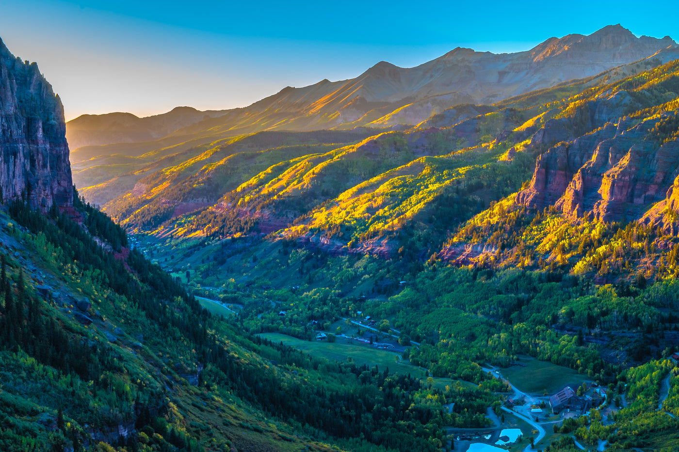Sunlit Telluride box canyon with the san miguel river flowing through and fields of green aspen trees